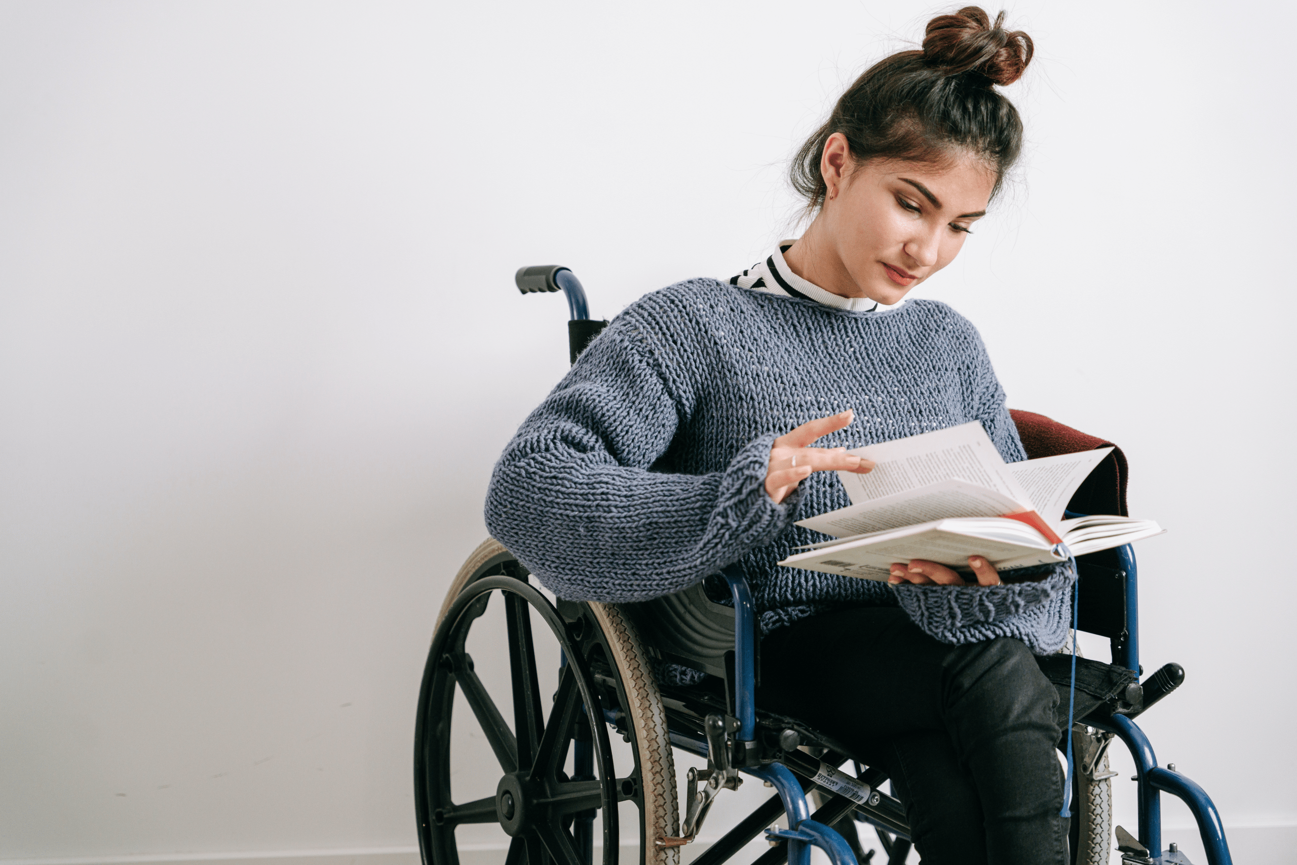 Lady with a red jacket, she is in a wheelchair looking forwards with a warm smile. She has her laptop, she is about to start a disability counselling session.