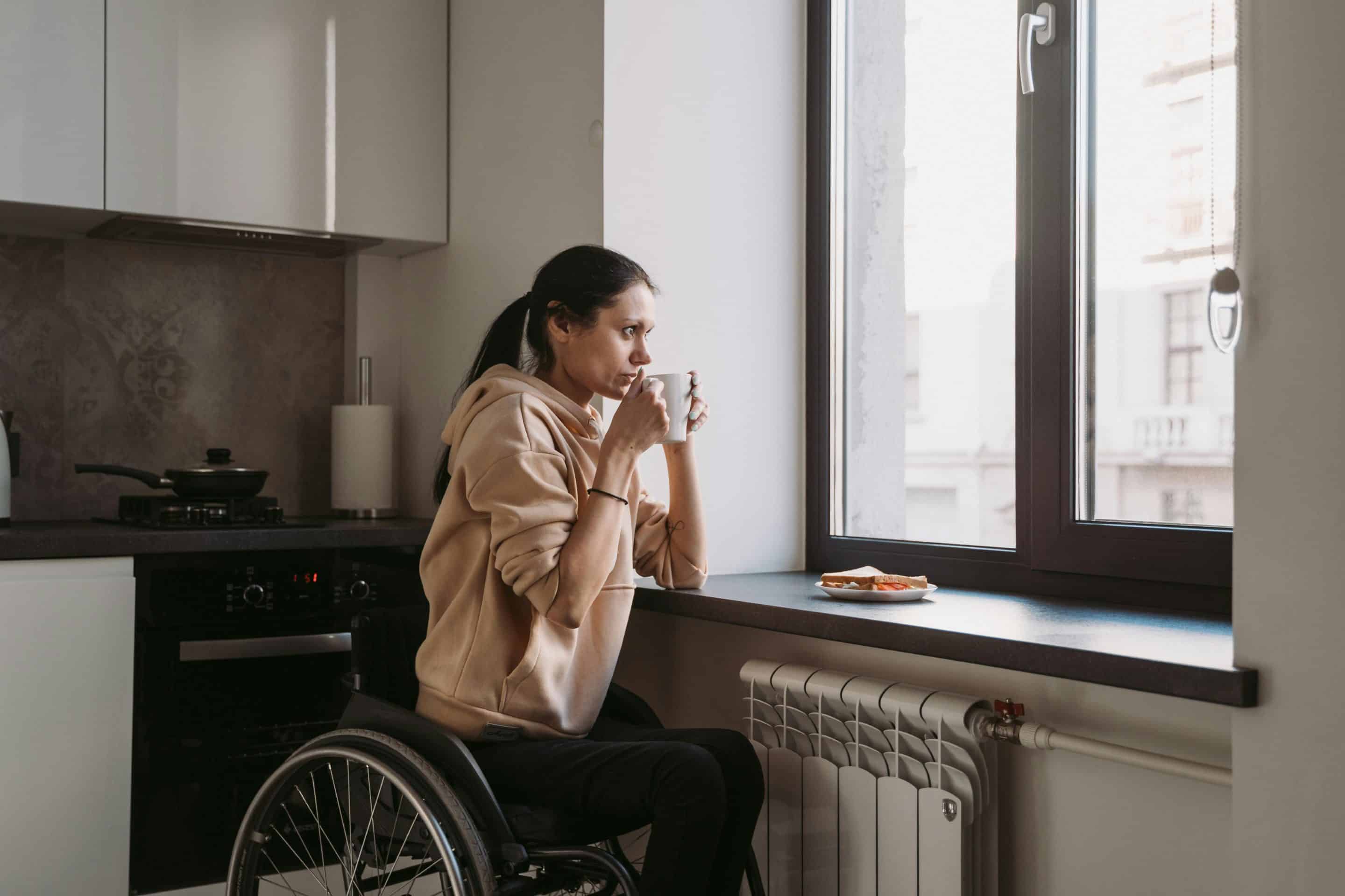 Lady with a red jacket, she is in a wheelchair looking forwards with a warm smile. She has her laptop, she is about to start a disability counselling session.